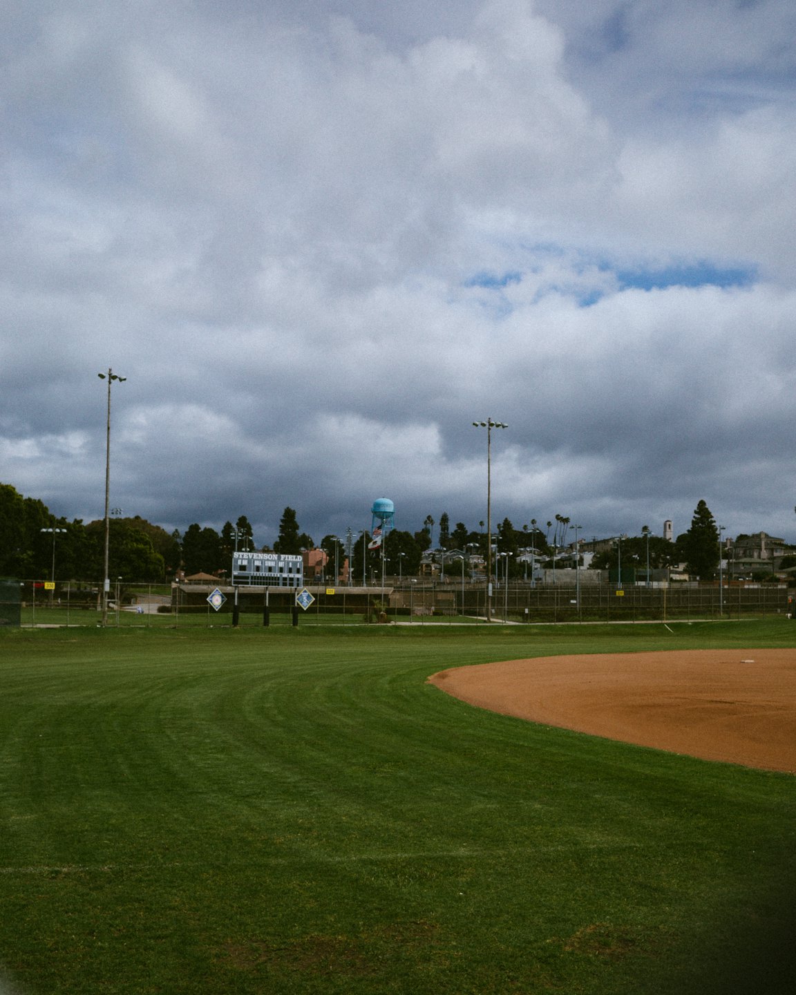 Empty baseball field with green grass and a dirt infield.